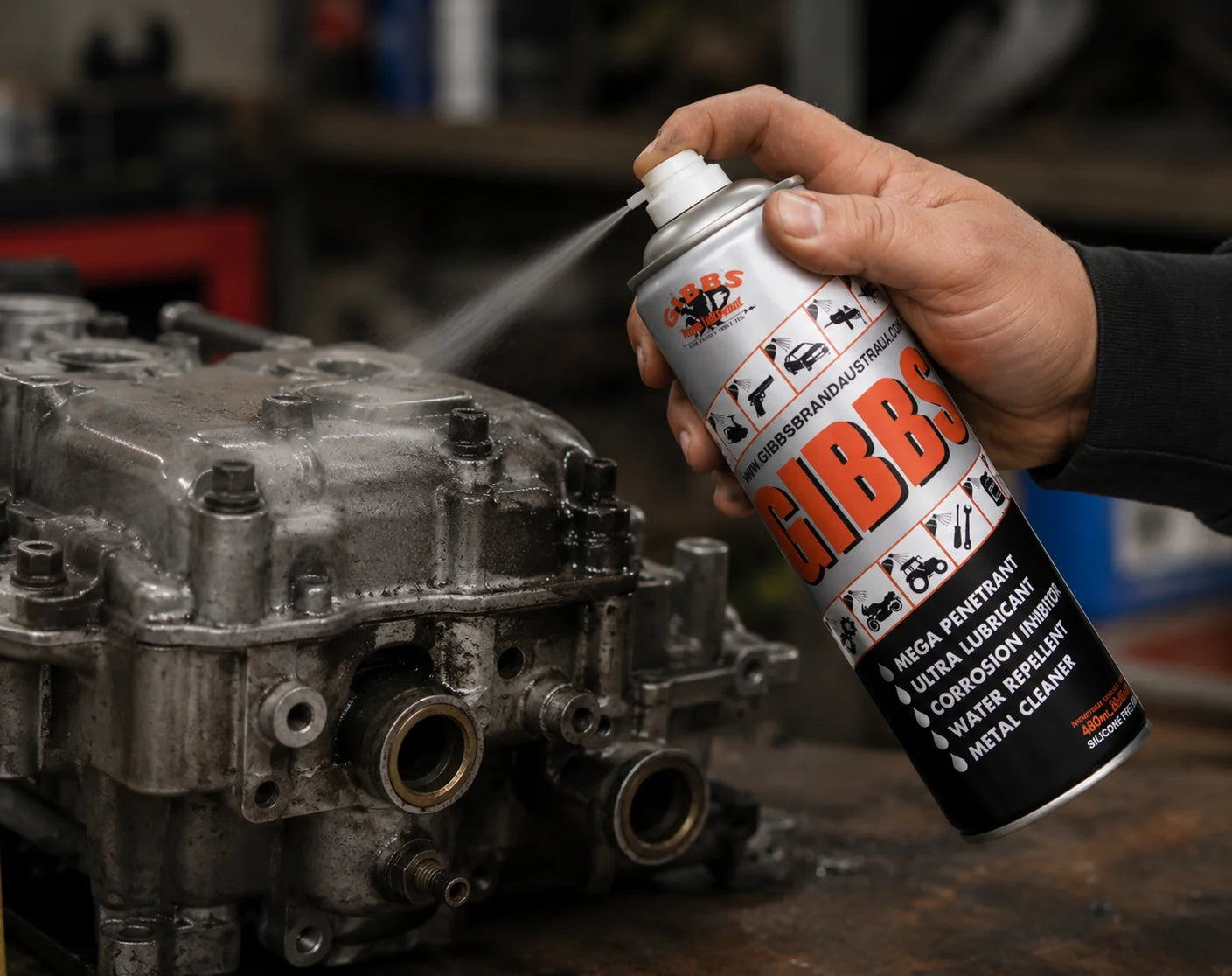 A hand spraying GIBBS onto a metal engine component